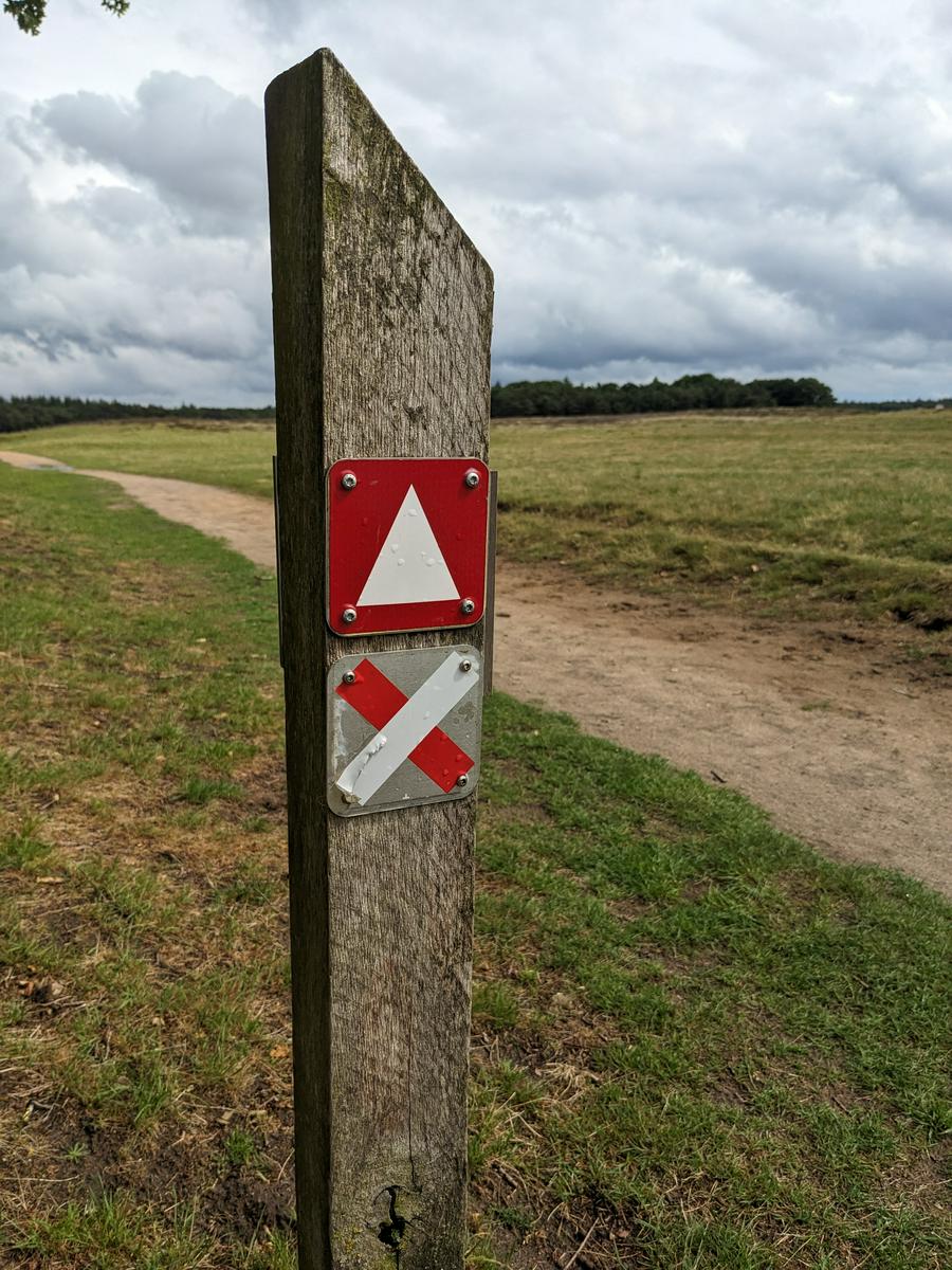 Close up of a route marker, big cumulus clouds in the distance.