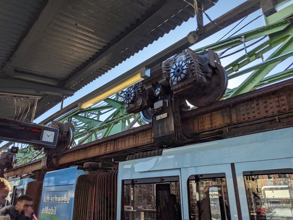 A picture of wheels and electric engines of the suspension railway in Wuppertal, sitting oddly atop the train, hanging from the tracks.