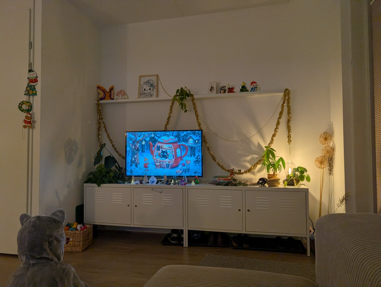 A look at a TV, playing Christmas-ish songs by a cat in apple-styled house, the furniture and background are decorated with tinsels and assorted Christmas trinkets