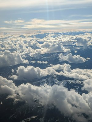 Aerial photo of the Alps, with snow covered peaks and green valleys in between.