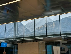 The insides of Innsbruck Airport, metal and glass, but a view of pristine mountains and cliff faces. A nice contrast between industrial and natural beauty.