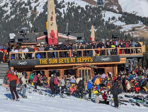 A piste bar called Seppi's, with a crowd of people sitting outside, enjoying the sun and drinks.