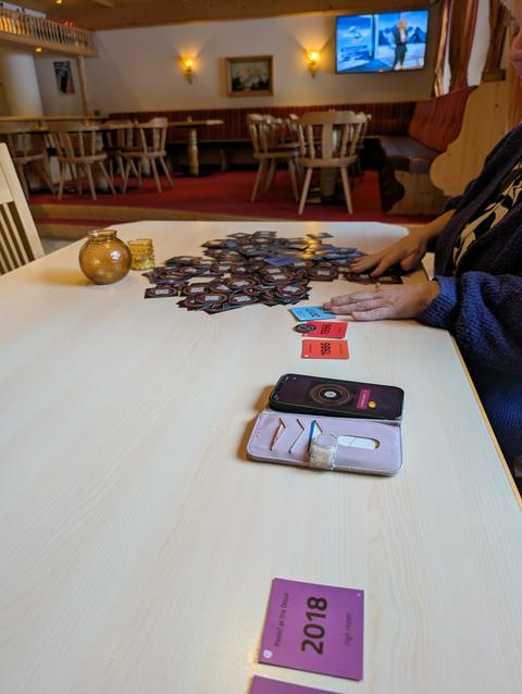 A bunch of cards spread on the table, a phone used to play songs