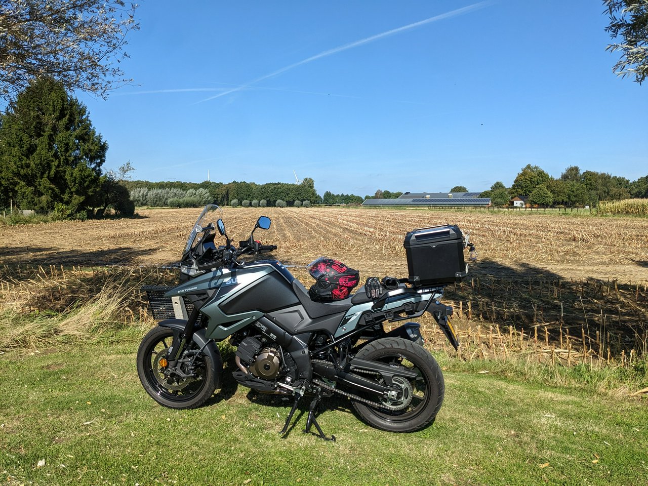 Motorcycle parked infront of a field, on a sunny day